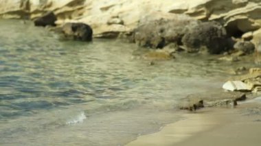 Şeffaf deniz mavi su taş sahile yıkar. Yunanistan