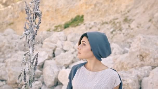 Joven mujer de pie sobre un fondo de montañas y piedras — Vídeos de Stock