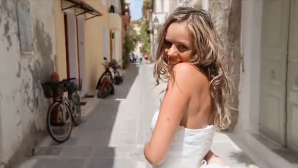 Glædelig legesyg brud på baggrund af smalle græske gader. Nygifte tilbringer en bryllupsrejse i Grækenland . – Stock-video
