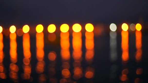 Luzes brilhantes são refletidas na água do mar escuro no cais com barcos. Bokeh... . — Vídeo de Stock