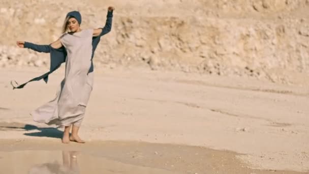 Menina graciosa em vestidos étnicos dançando perto do lago contra o fundo de uma rocha . — Vídeo de Stock
