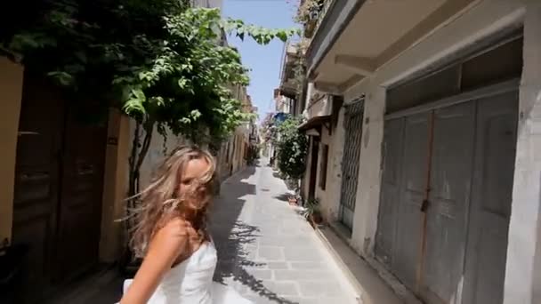 Feliz novia alegre corre por la calle de la ciudad vieja y mira hacia atrás . — Vídeo de stock