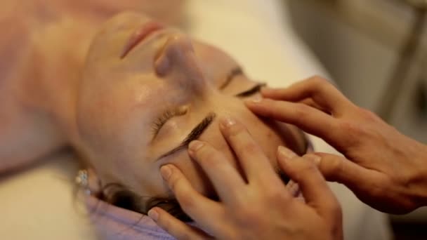 Masáž obličeje ve spa salonu krásy. Žena se těší relaxační masáž obličeje v kosmetologii lázeňském centru. — Stock video