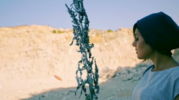 En ung kvinna står mot en bakgrund av berg och stenar med magiska gräs. Enchantress. svartvit bild — Stockvideo