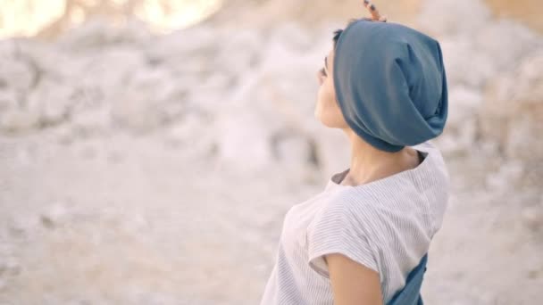 Mujer joven hermosa y soñadora sobre un fondo de montañas y piedras de primer plano . — Vídeos de Stock