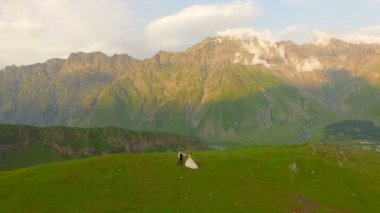 Mutlu gelin ve damat dağlar ve eski kilisenin arka planda. Gürcistan. havadan görünümü