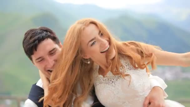 Joyeux marié et mariée sur fond de hautes montagnes. Le marié tourne autour de la mariée 