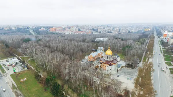 Вид з повітря на осінній парк, церква і дороги на тлі багатоповерхових будинків — стокове фото