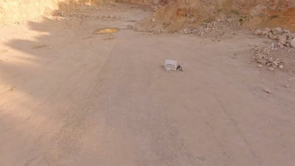 Fille assise sur les pierres près du piano sur le fond de sable jaune et les montagnes — Video