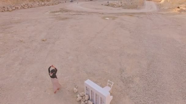 Szürreális terület. Egy lány és egy fehér zongora, a háttérben egy homokozó és egy teherautó légifelvételek. — Stock videók