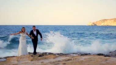 Mutlu gelin ve damat onların düğün günü yüksek dalgalar çerçevede bir sahil üzerinde.
