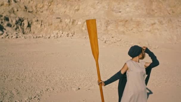 Slanke jonge vrouw met een peddel tegen de bergen. Surrealistische scene — Stockvideo