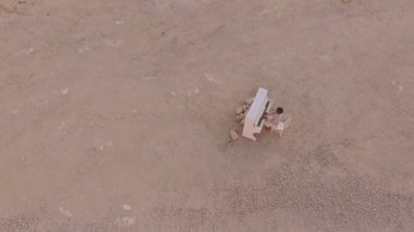 Genç adam sarı cliff bir arka plan üzerinde beyaz bir piyano üzerinde çalış. Havadan görünümü