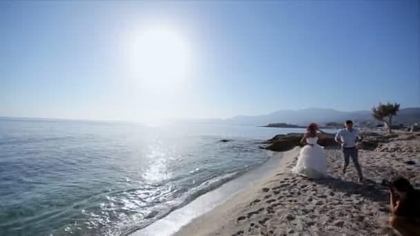 Счастливая молодожёны, бегающие по пляжу в день своей свадьбы — стоковое видео