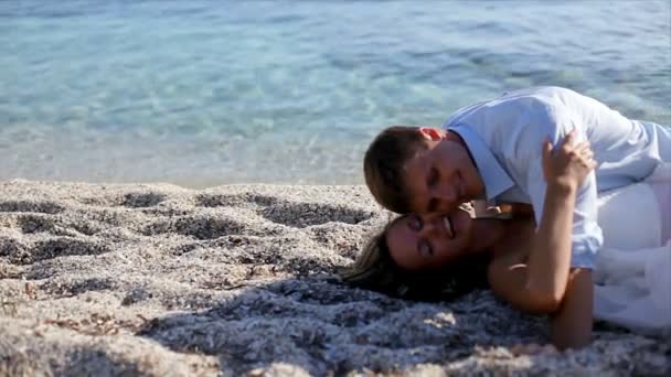 Gelukkig en vrolijk bruid en bruidegom zitten op het strand op hun trouwdag — Stockvideo