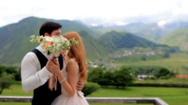 Güzel gelin ve damat bir buket çiçek bir arka planda görkemli Dağları ile