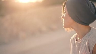 düşünceli üzgün kadın kumlu bir yol arka plan üzerinde oturur ve batan güneşin ışınları taş