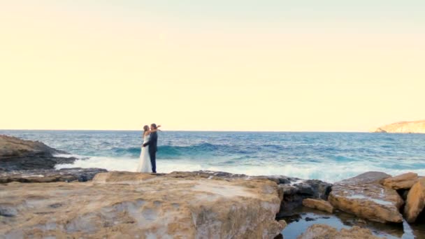 Glückliche Braut und Bräutigam umarmen sich am Hochzeitstag zärtlich am Meer. — Stockvideo