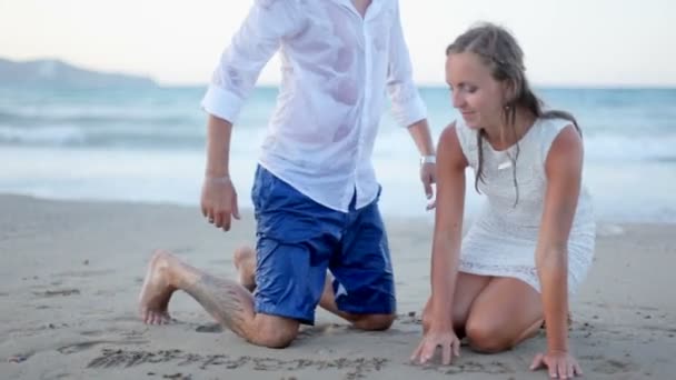 Feliz novia y novio abrazan tiernamente en la orilla del mar en el día de su boda . — Vídeos de Stock