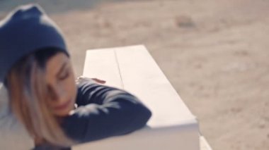 Güzel ve rüya gibi bir genç kadın piyano yakınındaki sarı kum oturur. Gerçek dışı arsa. yakın çekim.