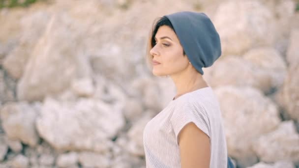 Retrato de una joven sobre un fondo de rocas y piedras. Orgullo, autoestima, arrogancia — Vídeo de stock