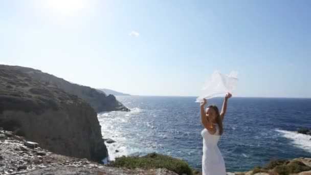 Uma noiva feliz está à beira-mar sob um véu de casamento agitando-se ao vento. O conceito de um casamento feliz e uma vida familiar feliz — Vídeo de Stock