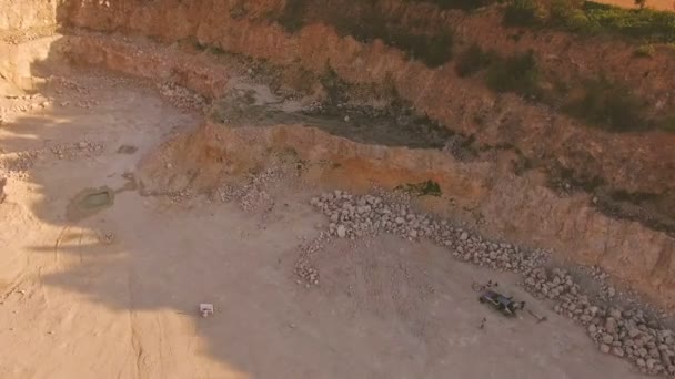 homme joue du piano dans un ravin profond. L'équipe de tournage se tient près de la voiture. Tournage aérien d'un vidéoclip dans une carrière de sable 