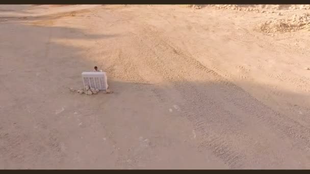 Homme joue du piano dans un ravin profond. Tournage aérien d'un vidéoclip dans une carrière de sable — Video