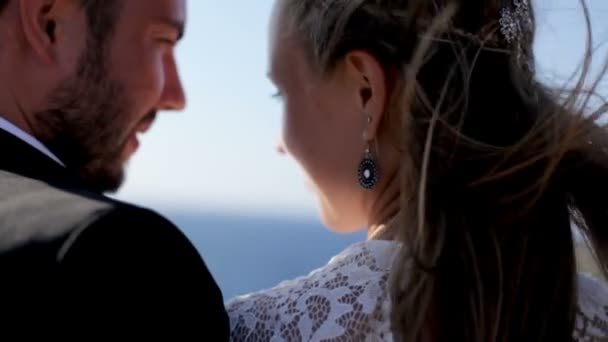 Glückliche Braut und Bräutigam umarmen sich am Hochzeitstag zärtlich am Meer. — Stockvideo