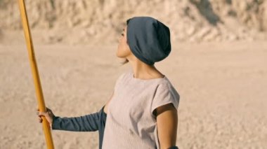 Kadın militan ve belirleyici birer kürek Dağları arka planı elinde tutar. Gerçeküstü sahne