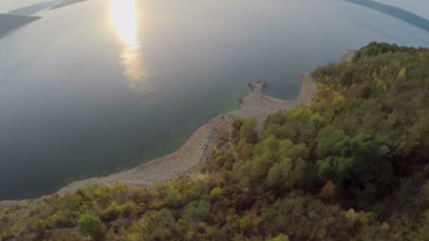 La novia y el novio admiran la hermosa vista del sol poniente en la orilla de un amplio río. vista aérea . — Vídeo de stock