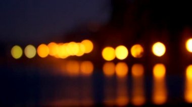 Gece parlak ışıklar deniz suyu çok katlı binaların arka planı yansıtılır. bokeh