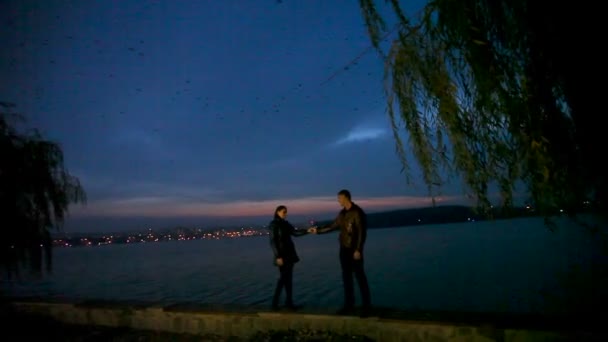 Guy lovingly embraces and kisses a girl against the backdrop of a night city — Stock Video