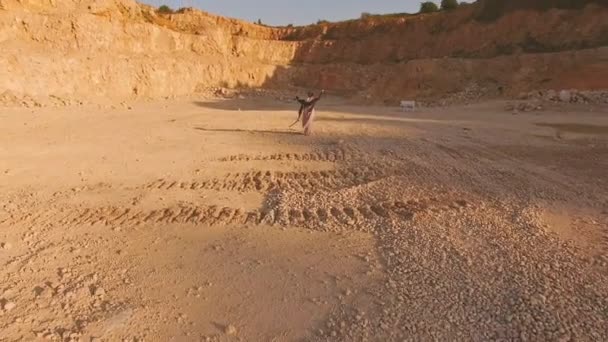 Eine junge Frau geht barfuß am gelben Sand zwischen den gelben Bergen entlang zum weißen Piano. Luftaufnahme. surrealistische Handlung. — Stockvideo