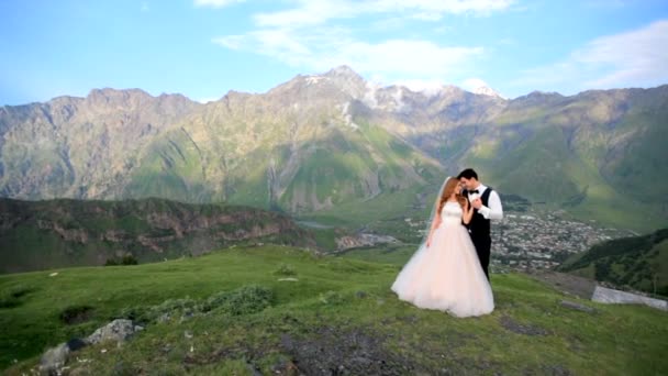 Bruden och brudgummen i bakgrunden i storslagen fjällmiljö. Georgien. Kazbegi. Bröllop fotosession — Stockvideo