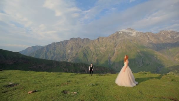 Enamorados recém-casados se divertir em uma maravilhosa noite de verão nos raios do sol poente contra o pano de fundo das montanhas majestosas — Vídeo de Stock