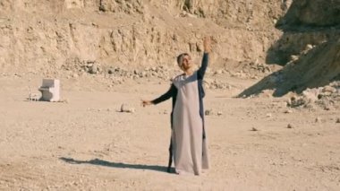 Güzel ve rüya gibi genç kadın bir arka planda dağlar ve ıssız bir bölgede beyaz bir piyano. Sürrealizm. Serap