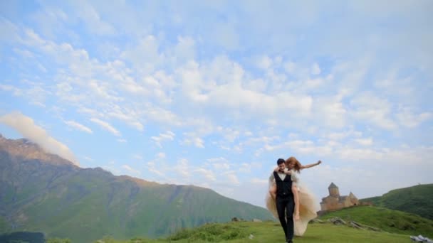 A menyasszony és a vőlegény jól érzik magukat, a nyári napsütésben a kék ég, fehér felhők alatt esküvő napján. Grúzia — Stock videók