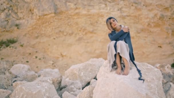 Junge Frau sitzt auf einem Felsen im Hintergrund der Berge — Stockvideo