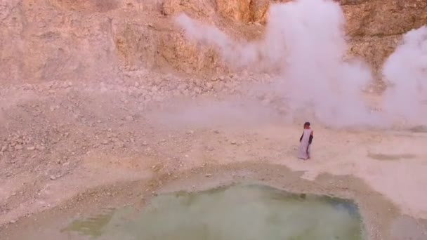 Mujer joven y elegante camina hacia el lago en las montañas contra un humo blanco. Vista aérea . — Vídeos de Stock