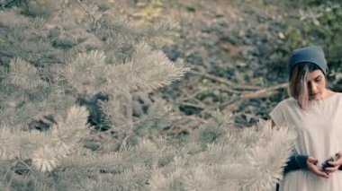 savurgan kadın bir çam ormanı içinde duruyor ve çam kozalakları onun elinde tutan.