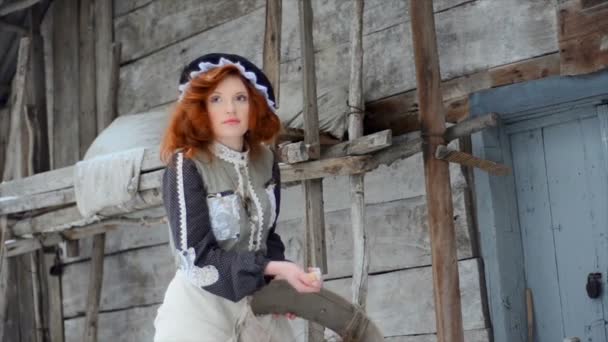 Jolie fille rousse est debout près de la vieille cabane en bois et vomit des graines de maïs — Video