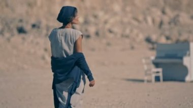 Yorgun genç kadın çıplak ayakla çakıl dağlar ve beyaz piyano arka plan üzerinde yürür