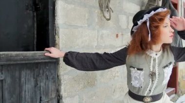 Güzel kızıl saçlı kız ormandaki eski ahşap kulübenin yanında duruyor..