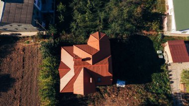Küçük bir köydeki yeni bir evin kırmızı çatısının havadan görünüşü. Döşemeli çatı