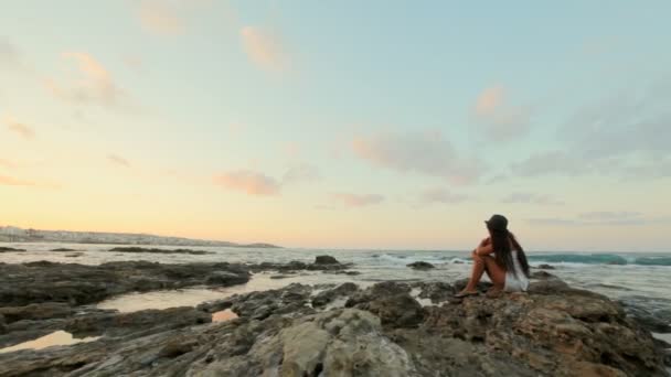 Romantisches Mädchen sitzt am steinernen Meeresufer und blickt in die Ferne — Stockvideo