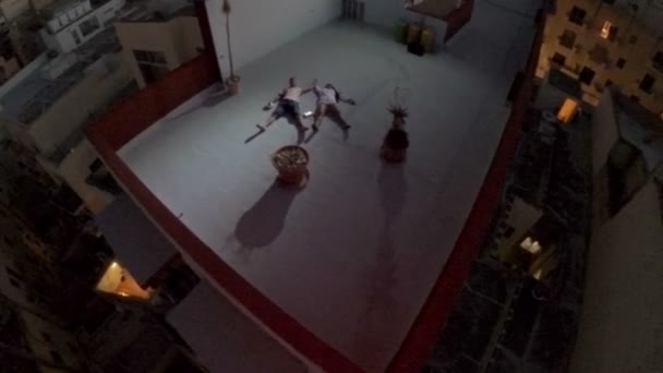 Surrealismo. Vista aérea. El tipo y la chica están en el techo de una casa alta por la noche en una gran ciudad — Vídeo de stock