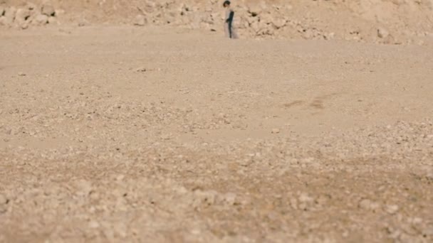 Jeune femme marche pieds nus à travers le désert au milieu d'une énorme montagne . — Video