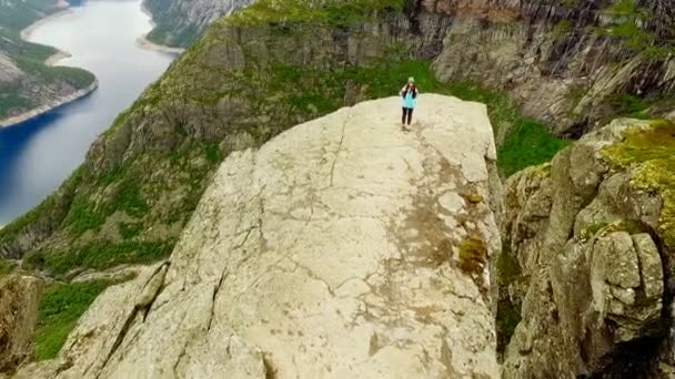 Noruega. Rapariga à beira da rocha Trolltunga. Veículo aéreo . — Vídeo de Stock