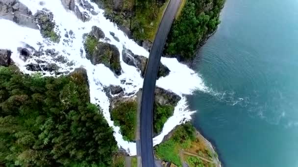 Νορβηγία. Ισχυρό και όμορφο καταρράκτη περνά κάτω από την εθνική οδό. Θέα από ψηλά. Εναέρια άποψη. — Αρχείο Βίντεο